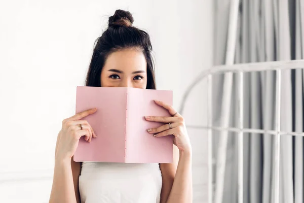 Young woman relaxing reading book on bed at home — Stock Photo, Image