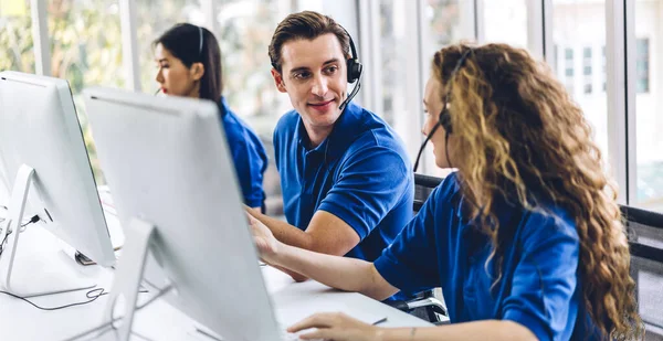 Mutlu çağrı merkezi gülümseme operatörü müşteri destek ekibi telefon hizmeti ajansı çağrı merkezindeki masaüstü bilgisayarında çalışıyor ve kulaklıkla konuşuyor