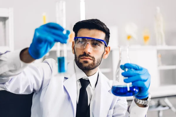 Professional scientist man research and working doing a chemical experiment while making analyzing and mixing  liquid in test tube.Young science man looking sample chemical on glass at laboratory