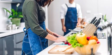 Masada taze sebze salatasıyla birlikte yemek pişiren çift. Mutfakta lezzetli bir yemek hazırlamak isteyen mutlu çift.