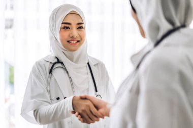 İki Asyalı Müslüman ortağın birlikte gülümsemesi doktor kadın tokalaşması. Profesyonel Müslüman doktor buluşması ve hastanede el sıkışması. Sağlık ve tıp.