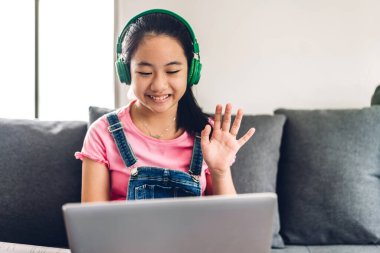 Okul çocuğu küçük kız öğreniyor ve dizüstü bilgisayara bakıyor ev ödevi yapıyor çevrimiçi eğitim sistemi ile bilgi öğreniyor. Evde öğretmenle çocuk video konferansı