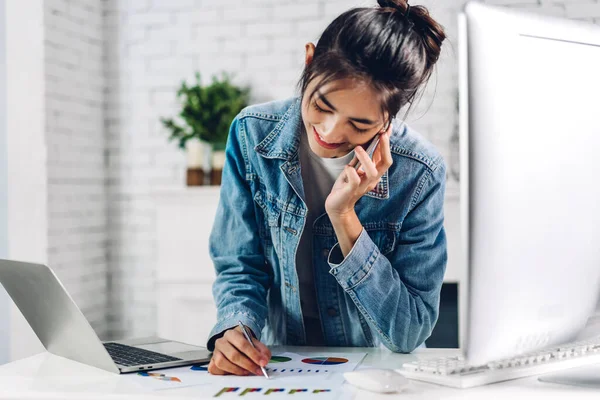 Young smiling happy asian woman relaxing using laptop computer working and video conference meeting online chat.Young creative girl look at business report paper at home.work from home concept