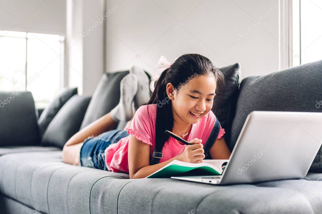 School kid little girl learning and looking at laptop computer making homework studying knowledge with online education e-learning system.children video conference with teacher tutor at home