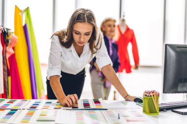 Moda tasarımcısı güzel bir kadının portresi renkli tekstil örnekleriyle çalışıyor. Mankenler ve renkli kumaşlarla çalışan son sınıf öğrencisi bir kadın.