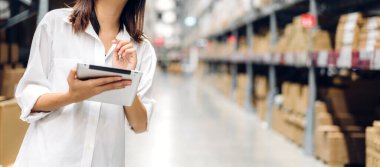 Depo 'daki ürün ve gereçlerin kontrol edilmesi için tablet bilgisayarında çalışan kadın portresi. Lojistik ve ticari ihracat.