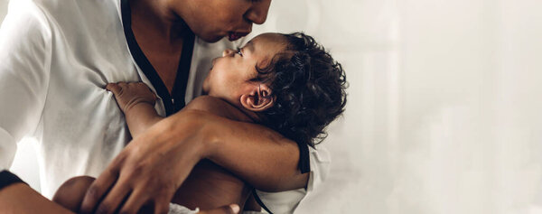 Portrait of enjoy happy love family african american mother playing with adorable little african american baby.Mom touching with cute son moments good time in a white bedroom.Love of black family concept