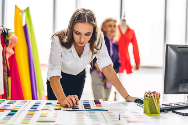 Moda tasarımcısı güzel bir kadının portresi renkli tekstil örnekleriyle çalışıyor. Mankenler ve renkli kumaşlarla çalışan son sınıf öğrencisi bir kadın.