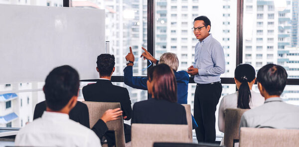 Бизнесмен, стоящий перед группой людей на семинаре консультационных совещаний в зале или помещении семинара.