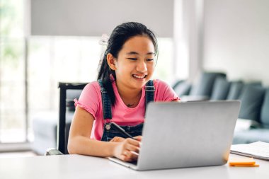 Okul çocuğu küçük kız öğreniyor ve dizüstü bilgisayara bakıyor ev ödevi yapıyor çevrimiçi eğitim sistemi ile bilgi öğreniyor. Evde öğretmenle çocuk video konferansı