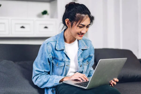 Young smiling happy beautiful asian woman relaxing using laptop computer working and video conference meeting at home.Young creative typing on keyboard.work from home concept