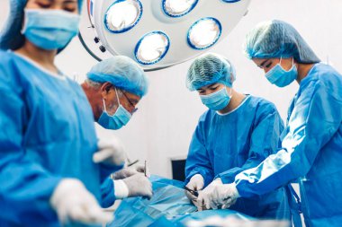 Profesyonel anestezi uzmanı doktor tıp ekibi ve asistanı modern hastane acil servisinde cerrahi ekipmanla jinekolojik ameliyata hazırlanıyor.