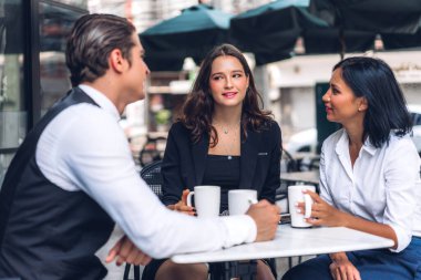 Bir grup neşeli genç arkadaş buluşmayı tartışıyor ve birlikte kahve içerek eğleniyorlar. Kafe masasında ve restoranda karışık ırkçı insanlar oturuyor.