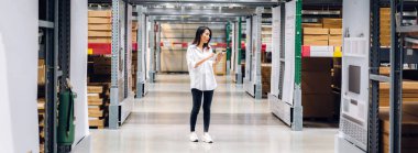 Gülümseyen Asyalı yönetici kadın portresi ayakta duruyor ve malzeme ve gereçleri depoda kontrol etmek için tablet bilgisayardan ayrıntılı talimat veriyor. Lojistik ve iş ihracatı