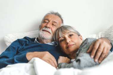 Üst düzey mutlu çift evde yatak odasında uzanıp sohbet ediyor. Emekliler konsepti.