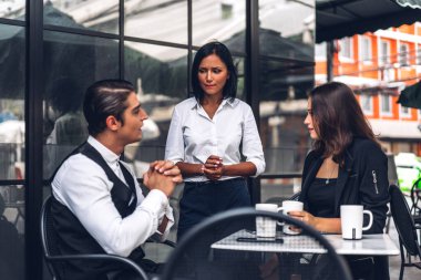 Bir grup neşeli genç arkadaş buluşmayı tartışıyor ve birlikte kahve içerek eğleniyorlar. Kafe masasında ve restoranda karışık ırkçı insanlar oturuyor.