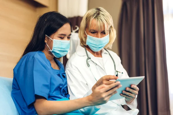 청진기를 사용하여 보호용 마스크를 나이든 의사는 병원에 타블렛으로 결과를 확인하는 — 스톡 사진