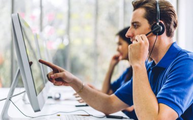Mutlu çağrı merkezi gülümseme operatörü müşteri destek ekibi telefon hizmeti ajansı çağrı merkezindeki masaüstü bilgisayarında çalışıyor ve kulaklıkla konuşuyor