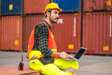 Miğferli profesyonel mühendis konteynır ustabaşı ayakta çalışıyor ve telsiz kullanıyor stokları yükleme için konteynıra koyuyor. Lojistik ve iş ihracatı