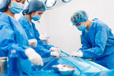 Profesyonel anestezi uzmanı doktor tıp ekibi ve asistanı modern hastane acil servisinde cerrahi ekipmanla jinekolojik ameliyata hazırlanıyor.