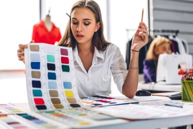 Moda tasarımcısı güzel bir kadının portresi renkli tekstil örnekleriyle çalışıyor. Mankenler ve renkli kumaşlarla çalışan son sınıf öğrencisi bir kadın.