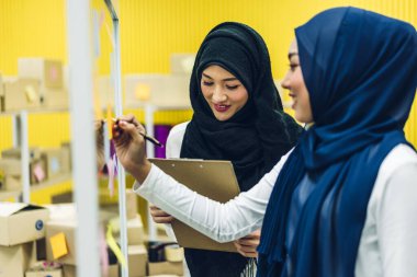 Yaratıcı, mutlu, mutlu, gülümseyen iki kolej. İki Müslüman iş kadını strateji analizi ve beyin fırtınası yapıyor. Ofisteki cam pencere projesine başlama projesini paylaşmak için çıkartma yapıştırıyor.