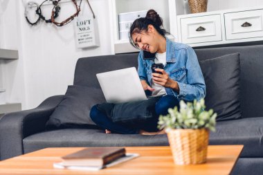 Dizüstü bilgisayarla çalışan ve evde video konferansı yapan genç bir kadın. Ev konseptinden çalışma.