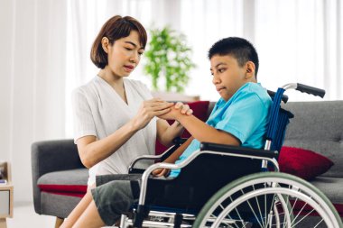 Asyalı fizyoterapistin portresi engelli çocuk sağlığı sorununa rehabilitasyon kliniğinde tekerlekli sandalyede oturarak yardım ve oyun oynayarak yardımcı oluyor.