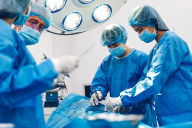 Profesyonel anestezi uzmanı doktor tıp ekibi ve asistanı modern hastane acil servisinde cerrahi ekipmanla jinekolojik ameliyata hazırlanıyor.