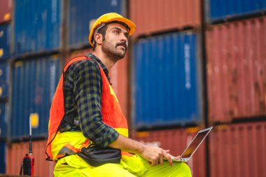 Miğferli profesyonel mühendis konteynır ustabaşı ayakta çalışıyor ve telsiz kullanıyor stokları yükleme için konteynıra koyuyor. Lojistik ve iş ihracatı