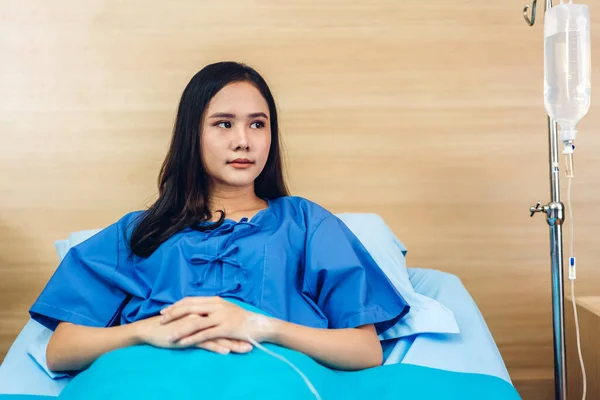 Portrait of smiling asian woman patient sitting on bed looking at camera with health medical care express trust and Insurance concept in room at hospital