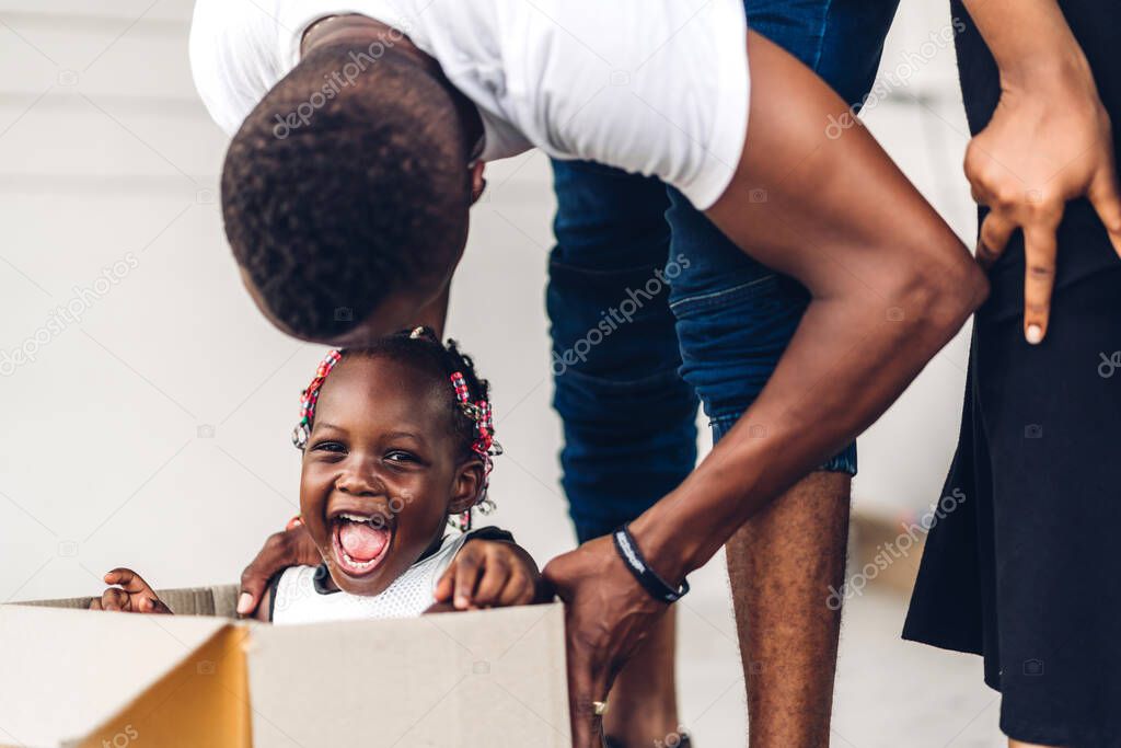 Portrait of enjoy happy love black family african american father and mother with little african girl smiling sitting in cardboard box at new home unpacking during move and having fun moments good time