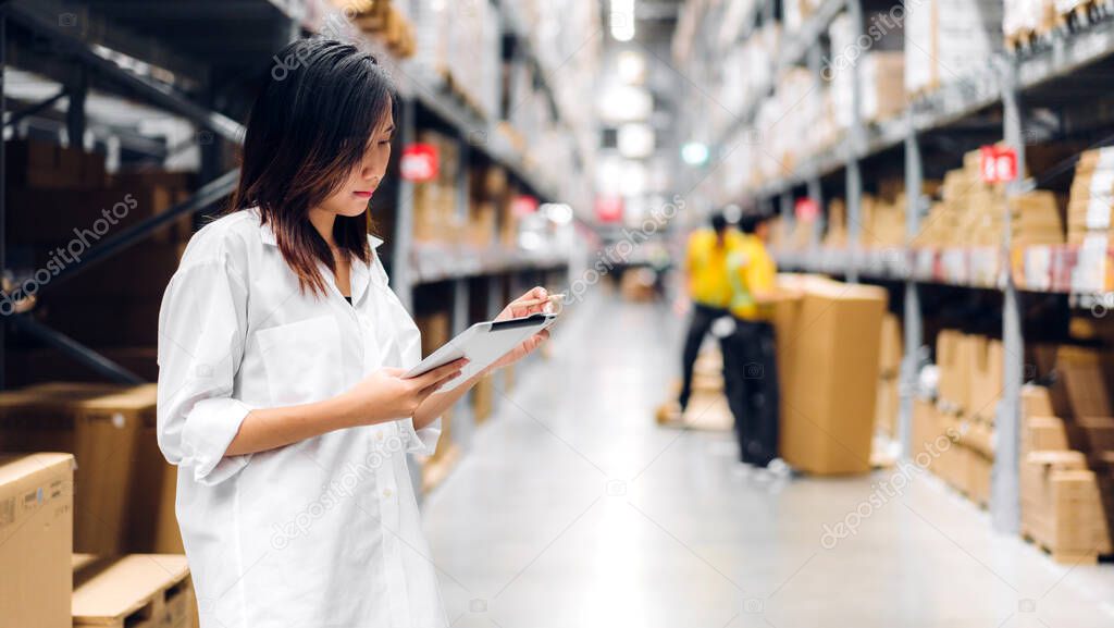 Portrait of smiling asian manager worker woman standing and order details on tablet computer for checking goods and supplies on shelves with goods background in warehouse.logistic and business export