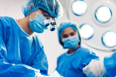 Profesyonel anestezi uzmanı doktor tıp ekibi ve asistanı modern hastane acil servisinde cerrahi ekipmanla jinekolojik ameliyata hazırlanıyor.