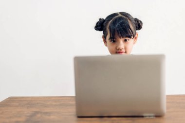 Okul çocuğu küçük kız öğreniyor ve dizüstü bilgisayara bakıyor ev ödevi yapıyor çevrimiçi eğitim sistemi ile bilgi öğreniyor. Evde öğretmenle çocuk video konferansı