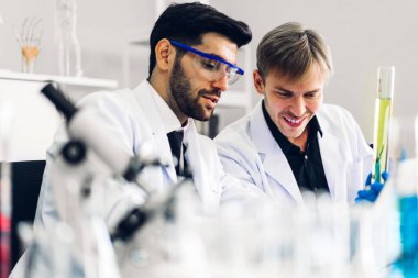 Profesyonel iki bilim adamı test tüpünde sıvı analiz ederken ve karıştırırken kimyasal bir deney yapıyor. Genç bilim adamı laboratuvarda cam üzerine kimyasal örnekler bırakıyor.