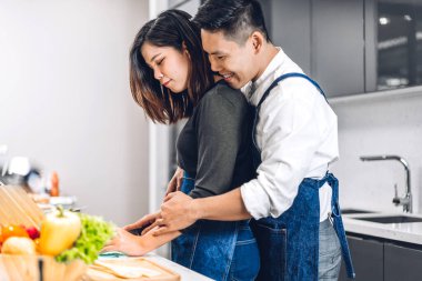 Masada taze sebze salatasıyla birlikte yemek pişiren çift. Mutfakta lezzetli bir yemek hazırlamak isteyen mutlu çift.