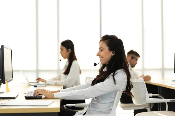 Group of happy asian smiling call center business operator customer support team phone services agen working and talking with headset on desktop computer at call center