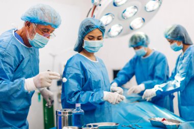Profesyonel anestezi uzmanı doktor tıp ekibi ve asistanı modern hastane acil servisinde cerrahi ekipmanla jinekolojik ameliyata hazırlanıyor.