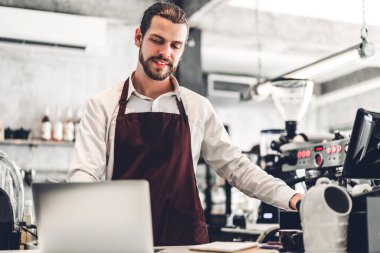 Yakışıklı sakallı baristanın portresi. Küçük işletme sahibi. Kafenin arkasında bilgisayarla çalışıyor.