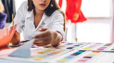 Moda tasarımcısı güzel bir kadının portresi. Renkli tekstil örnekleri ve renkli kumaşlarla çalışıyor.