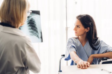 Steteskoplu üniforma giyen kıdemli kadın doktor, hasta kadın hastalara hastanede röntgen ile yapılan kontrol sonuçları hakkında konuşma ve danışmanlık desteği sağlıyor.