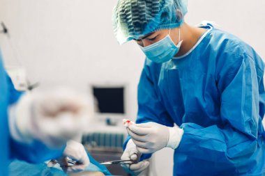 Profesyonel anestezi uzmanı doktor tıp ekibi ve asistanı modern hastane acil servisinde cerrahi ekipmanla jinekolojik ameliyata hazırlanıyor.