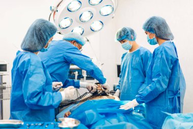 Profesyonel anestezi uzmanı doktor tıp ekibi ve asistanı modern hastane acil servisinde cerrahi ekipmanla jinekolojik ameliyata hazırlanıyor.