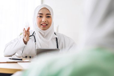 Müslüman Asyalı kadın doktor hastanede Müslüman kadına danışmanlık yapıyor ve kontrol ediyor. Kadın hasta. Sağlık ve ilaç tedavisi görmüş.