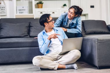 Genç Asyalı çift dizüstü bilgisayarlarını kullanarak rahatlıyor. İnternetteki video konferansında sohbet ediyorlar. Evde yaratıcı iş çifti planlama ve beyin fırtınası yapıyorlar.