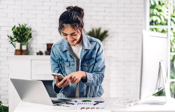 Young smiling happy asian woman relaxing using laptop computer working and video conference meeting online chat.Young creative girl look at smartphone at home.work from home concept