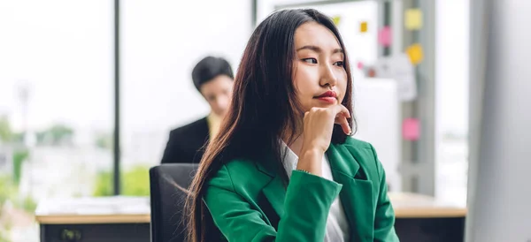 Beautiful confident asian businesswoman looking at desktop computer while sitting on office desk.Young creative coworkers business people working and planning