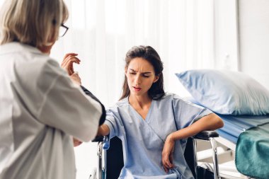 Steteskopla üniforma giyen kıdemli kadın doktor, hasta kadın hastalarla hastane kontrolleri hakkında konuşmak ve danışmak konusunda destek oluyor.
