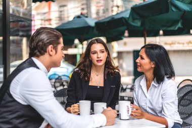 Bir grup neşeli genç arkadaş buluşmayı tartışıyor ve birlikte kahve içerek eğleniyorlar. Kafe masasında ve restoranda karışık ırkçı insanlar oturuyor.